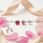 Pinkish red solitaire earrings, close-up view